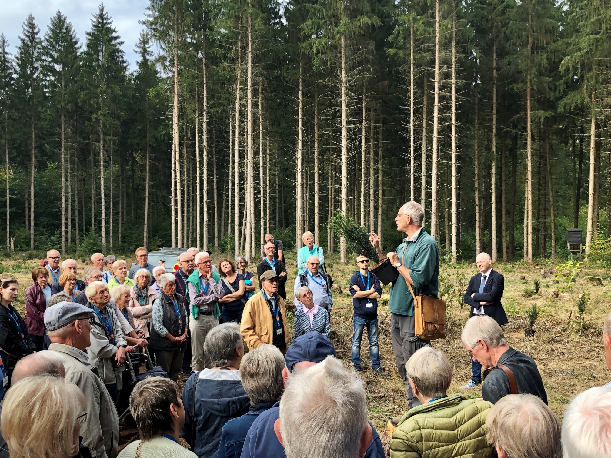Revierförster Burkhard Böer erklärt die Baumarten der Setzlinge, welche die Mitglieder-Jubilare der VR-Bank Ludwigsburg im Sachsenheimer Wald pflanzen. Foto: VR-Bank Ludwigsburg.