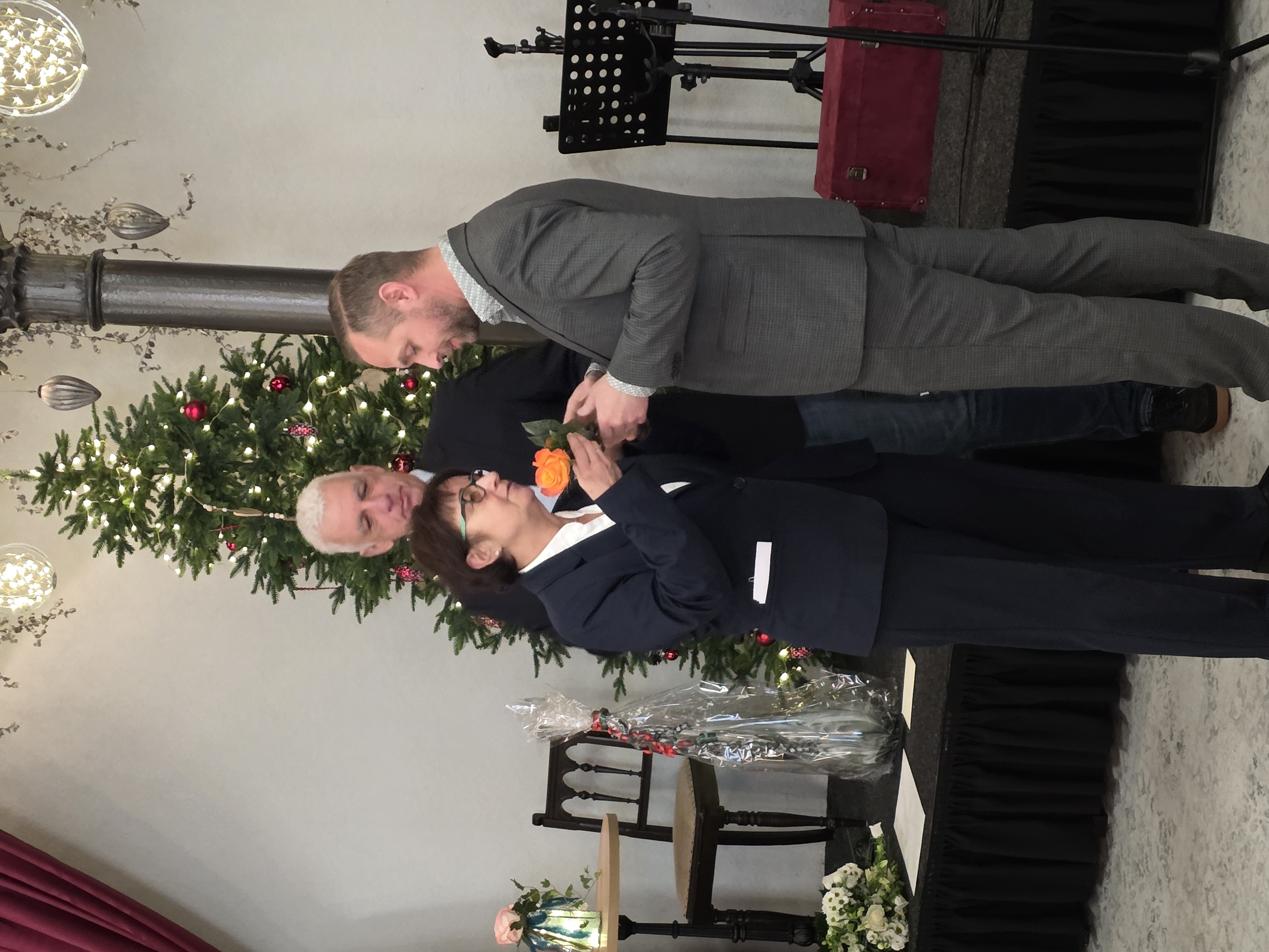 eine Frau übergibt einen Schlüssel mit Rose an einen Mann vor einer Bühne