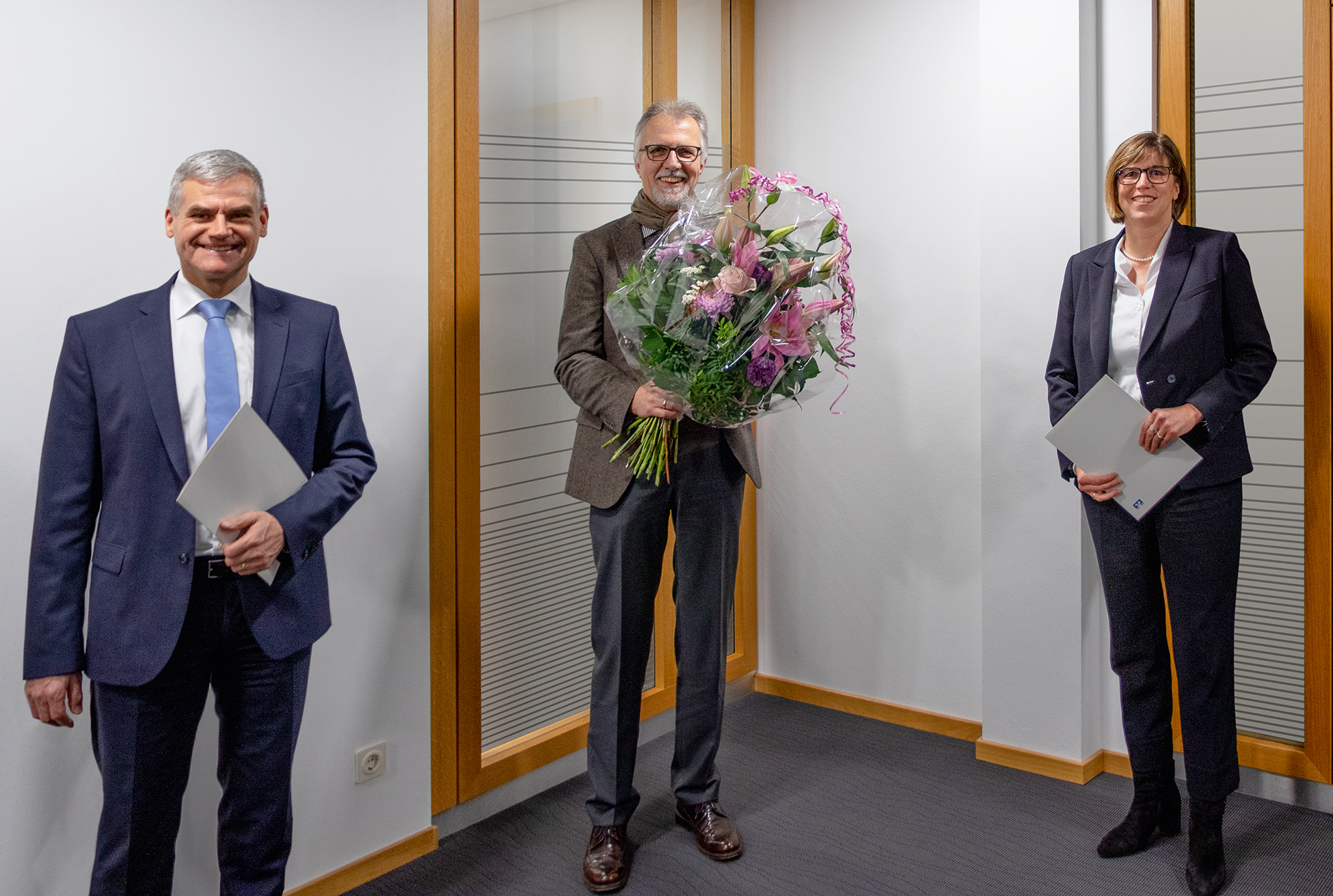 Der AR-Vorsitzende Roland Denecke -Bildmitte- überreicht Frau Kalbhenn und Herrn Vey die Bestellungsurkunde zum Vorstand.