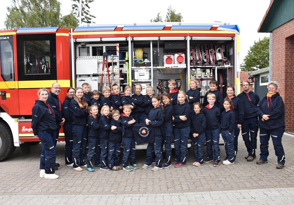 Mitglieder der Kinderfeuerwehr Neu Gülze/Zahrensdorf stehen gemeinsam mit ihren Betreuerinnen und Betreuern vor dem Feuerwehreinsatzfahrzeug